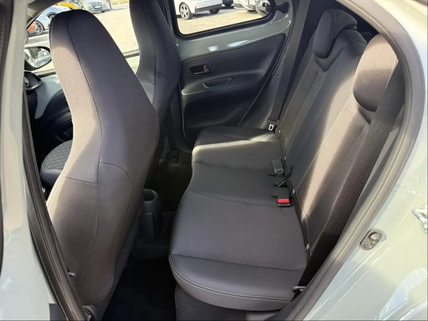 Vue intérieure côté droit sur les sièges arrière noirs de la Toyota Aygo X 2025, avec porte ouverte et tissu uni.
