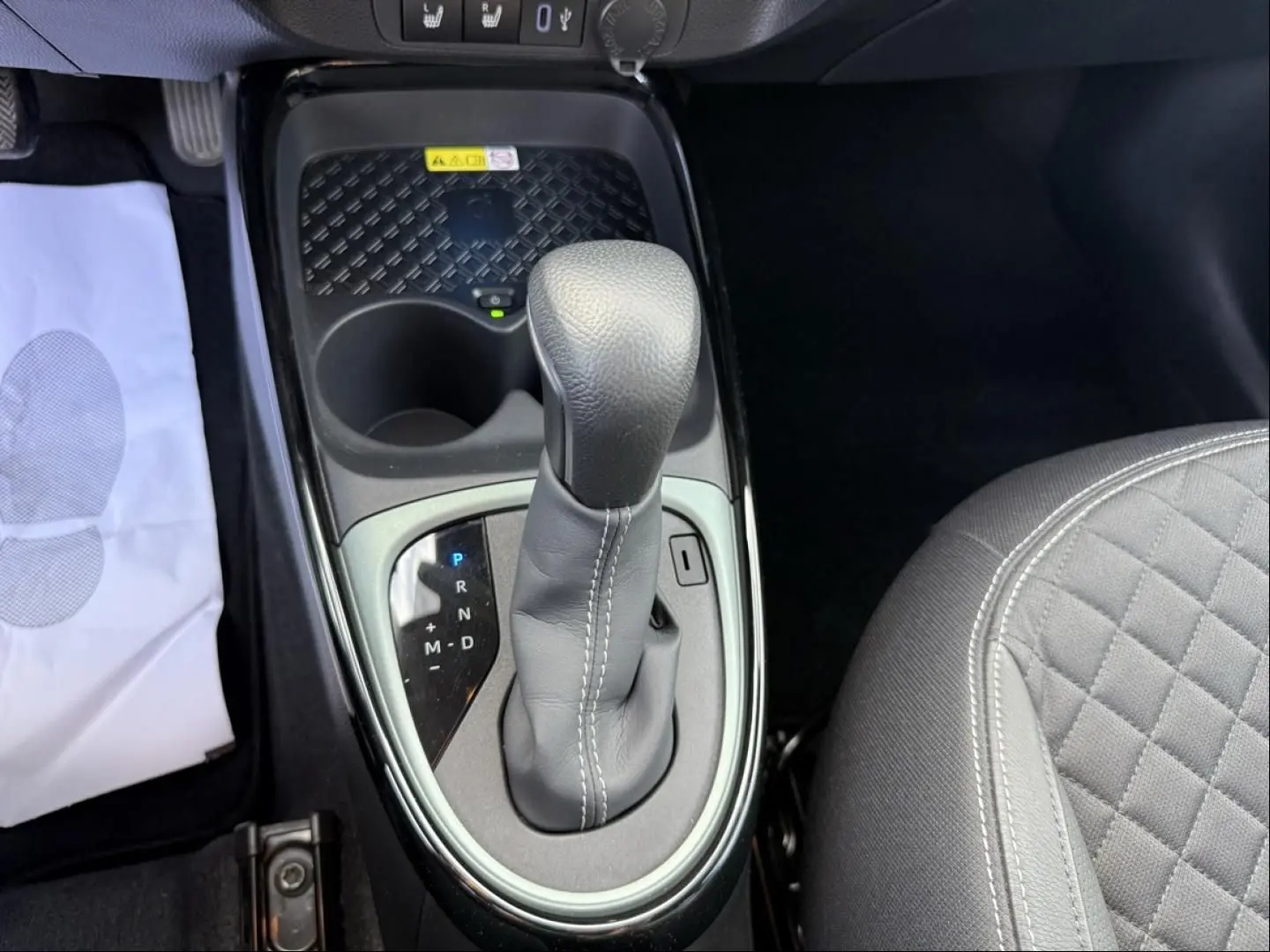 Gros plan sur le levier de vitesse automatique de la Toyota Aygo X 2025, intérieur noir avec surpiqûres blanches.