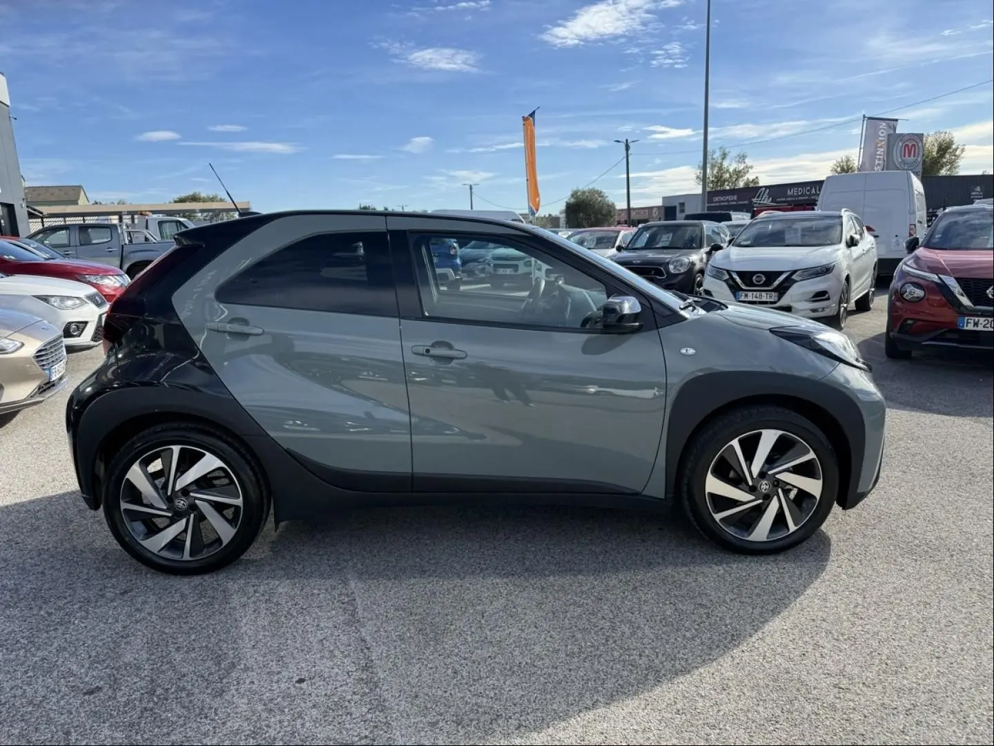 Vue de profil côté gauche d'une Toyota Aygo X 2025 vert aventurine avec toit noir et jantes distinctives en alliage.