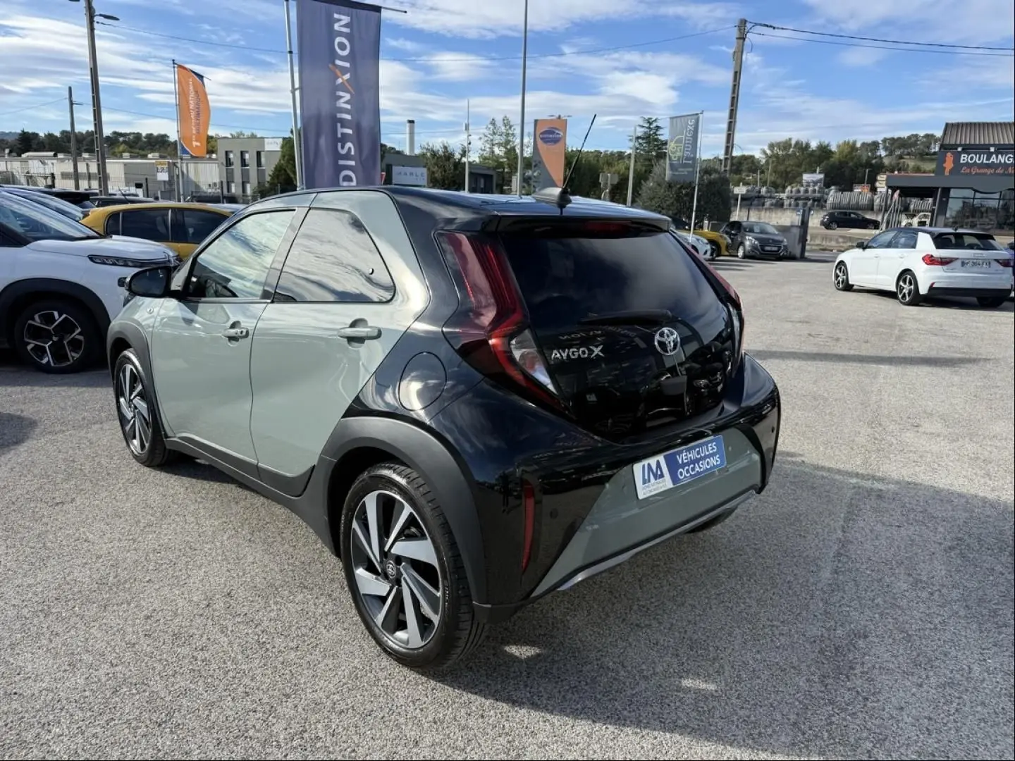 Vue 3/4 arrière droite d'une Toyota Aygo X 2025 vert aventurine avec toit noir et feux arrière distinctifs en forme de boomerang.