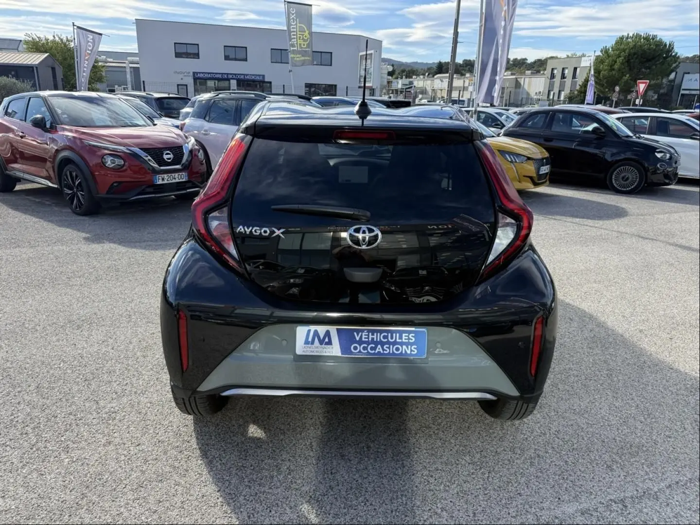 Vue arrière d'une Toyota Aygo X 2025 en vert aventurine avec toit noir, feux arrière en forme de boomerang.
