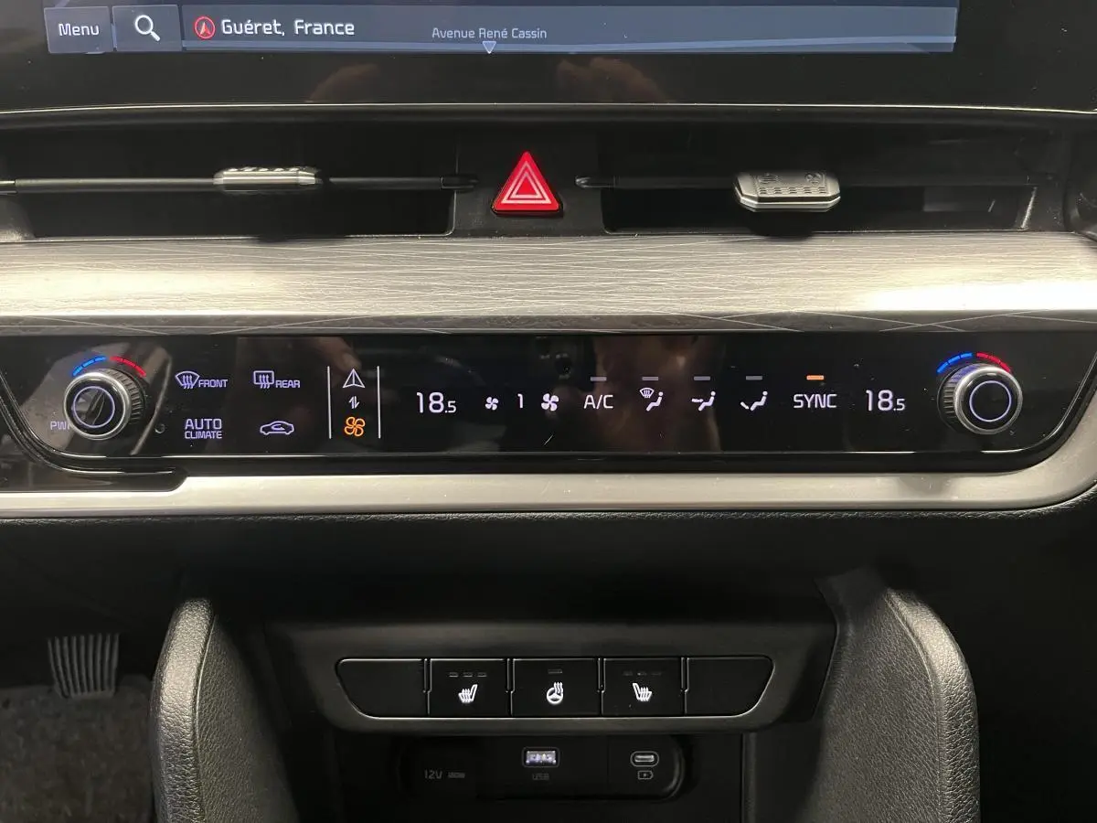 Plan rapproché du tableau de bord du Kia Sportage 2022 gris montrant la commande de climatisation automatique et les boutons chauffants.