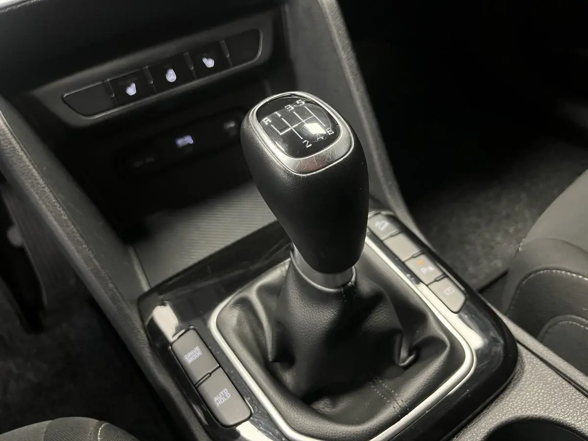 Le levier de vitesses manuel noir du Kia Sportage 2022, entouré de commandes et console centrale sombre.