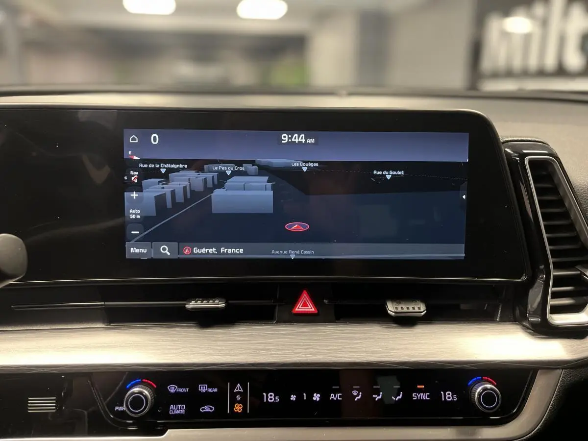 Tableau de bord du KIA SPORTAGE 2022 avec écran tactile GPS et commandes de climatisation affichant 18,5°C.