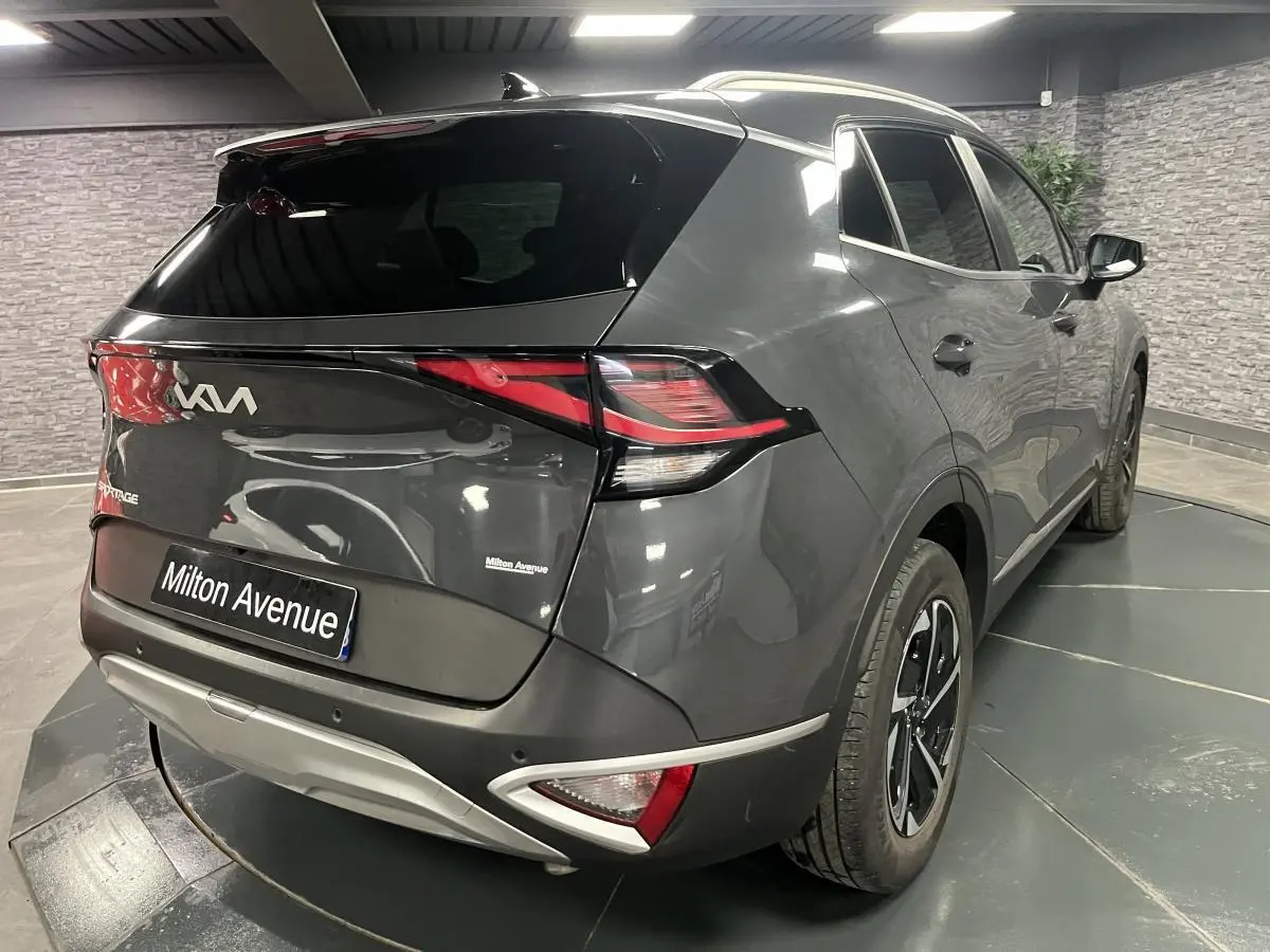 Vue 3/4 arrière droite du Kia Sportage gris métallisé 2022 avec feux arrière LED et jantes alliage 17 pouces.