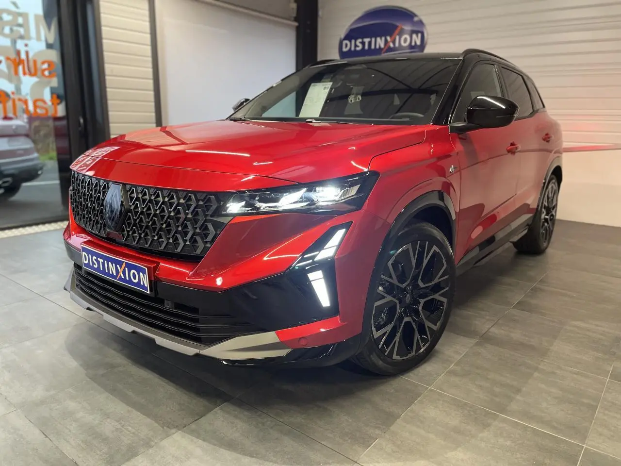 Renault Austral rouge métallisé avec toit noir, vue 3/4 avant droit, calandre noire et jantes alliage 20 pouces.