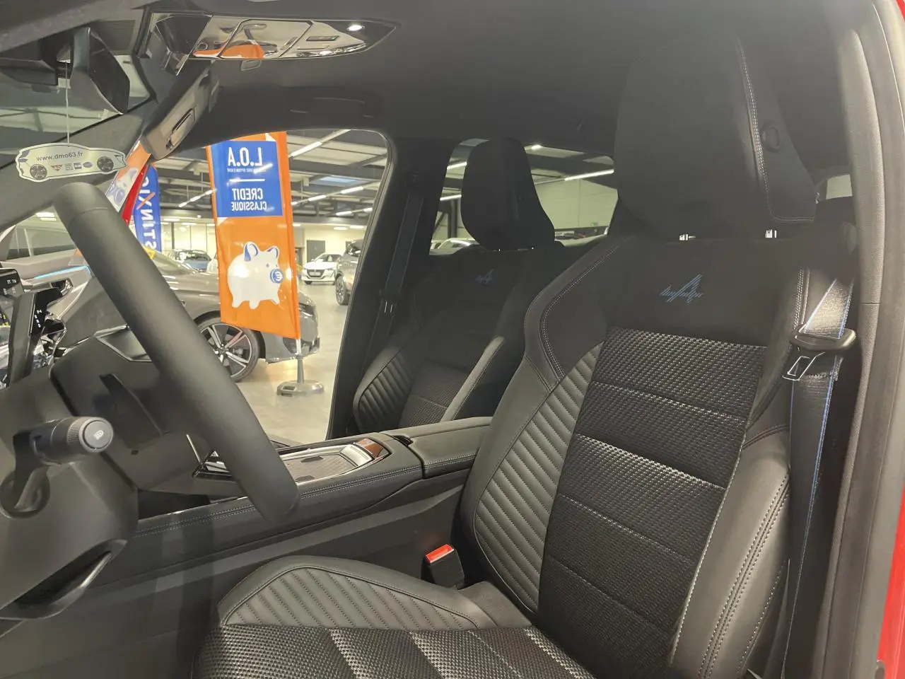 Intérieur côté conducteur du Renault Austral rouge, sièges sport Alcantara avec surpiqûres bleu blanc rouge et logo Alpine.