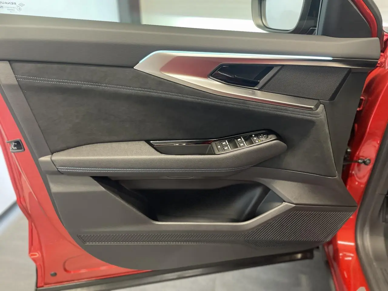 Vue latérale du panneau de porte avant gauche rouge métallisé du Renault Austral Esprit Alpine avec garniture noire et commandes électriques.