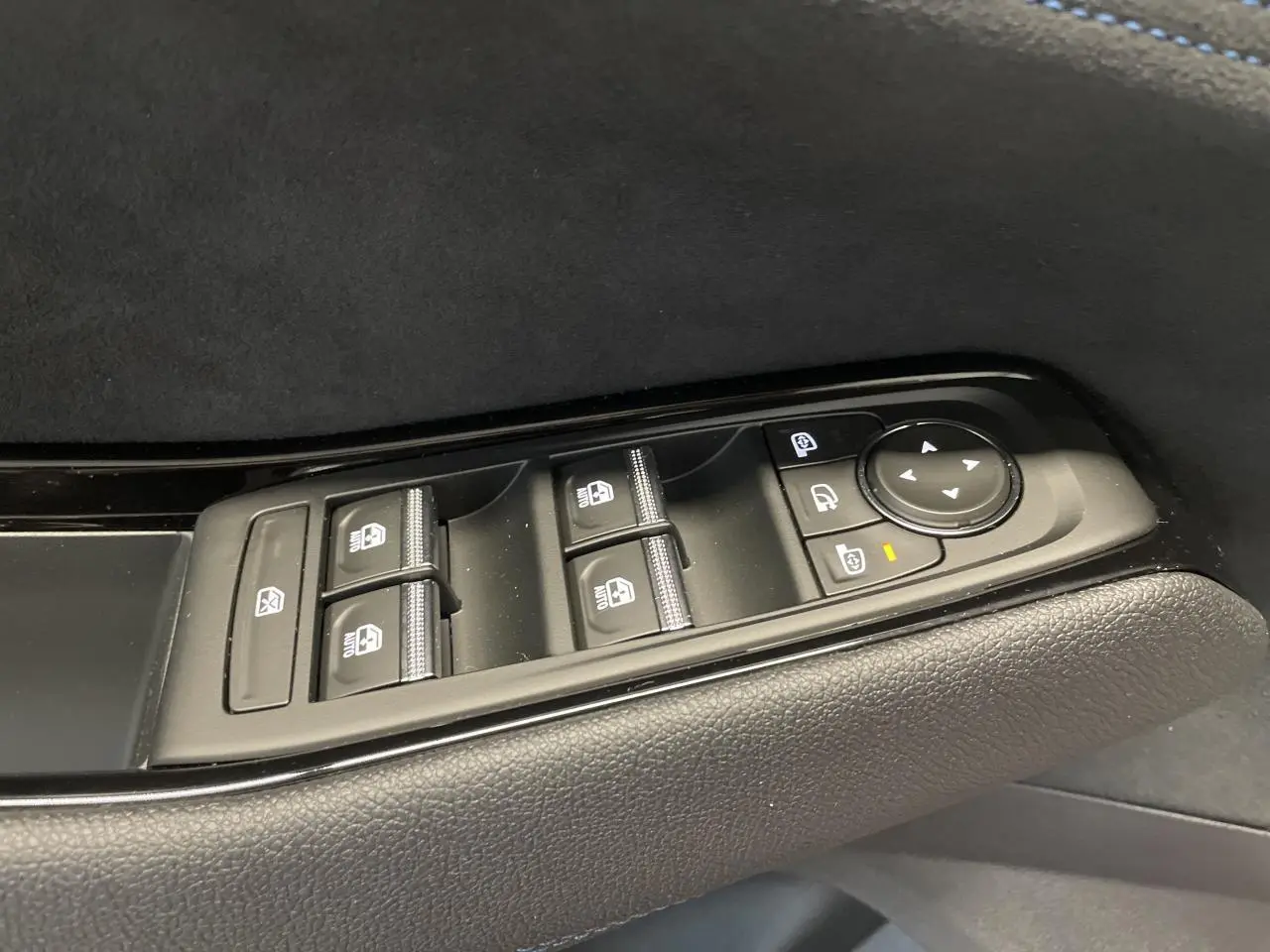 Gros plan sur les commandes de lève-vitres et rétroviseurs côté gauche en finition noire Alcantara du Renault Austral 2025.