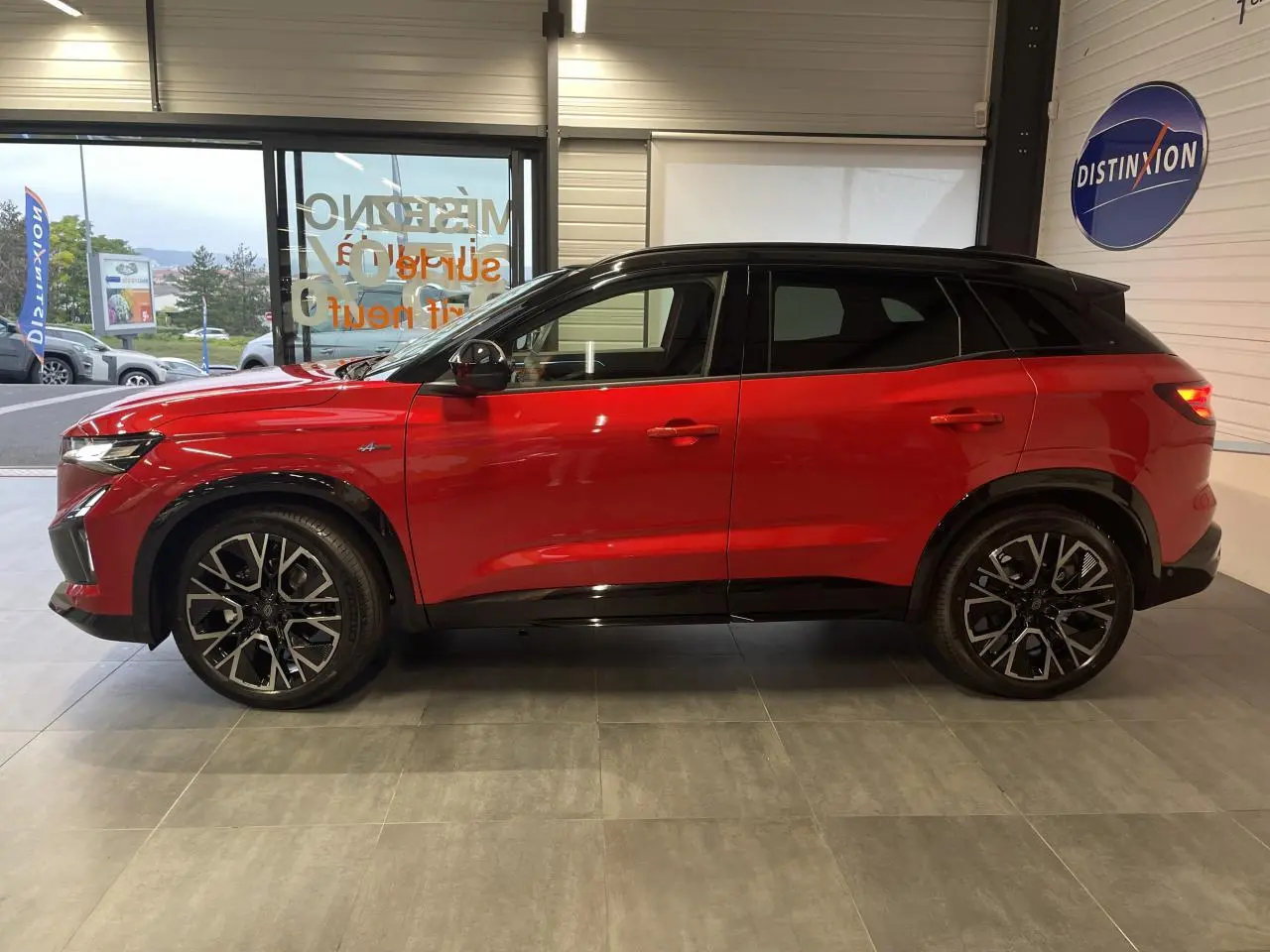 Profil côté gauche du Renault Austral rouge métallisé avec toit noir et jantes alliage 20 pouces en intérieur showroom.