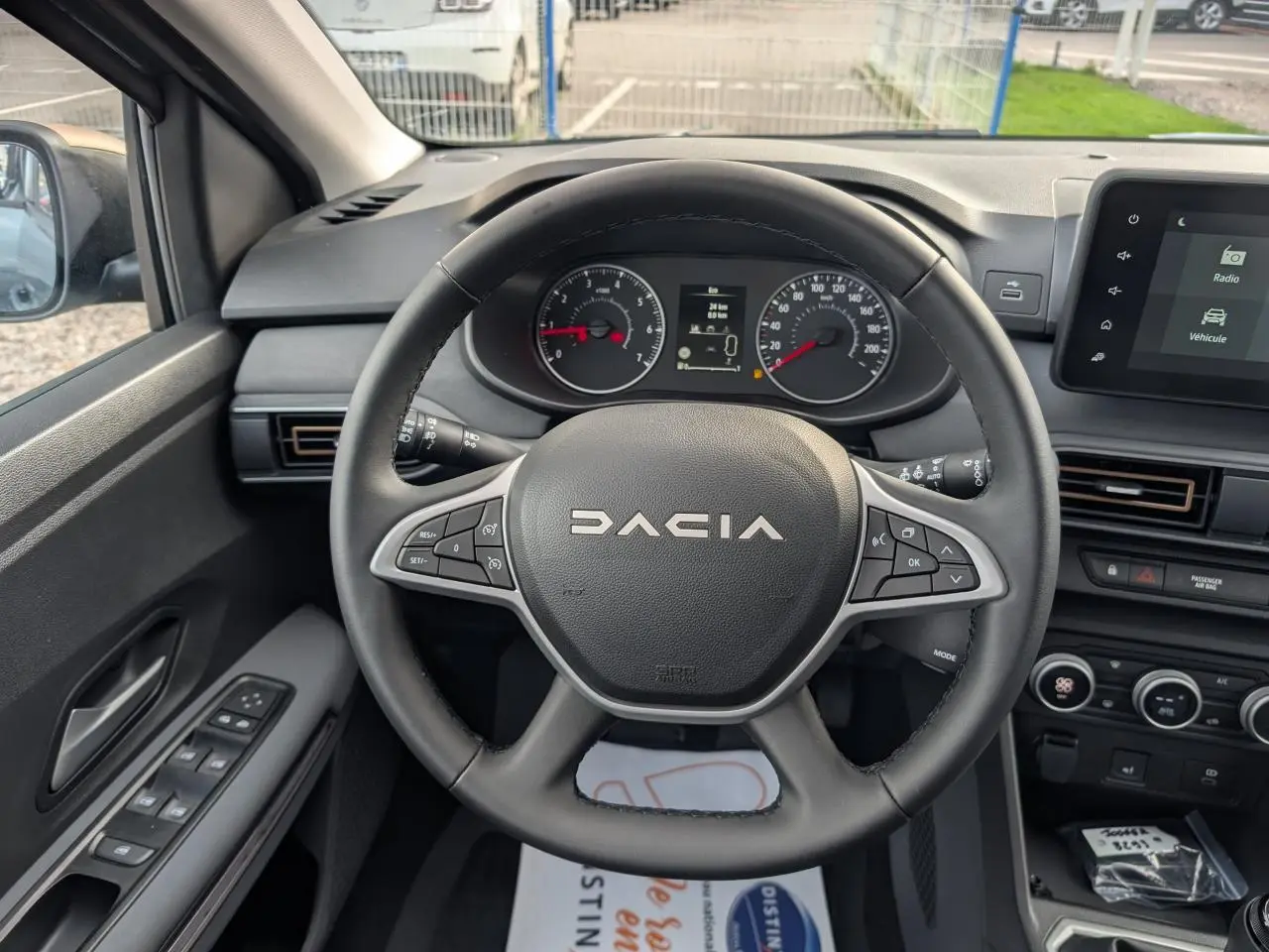 Vue intérieure centrée sur le volant noir Dacia et le tableau de bord avec écran tactile du Dacia Jogger gris métallisé 2025.