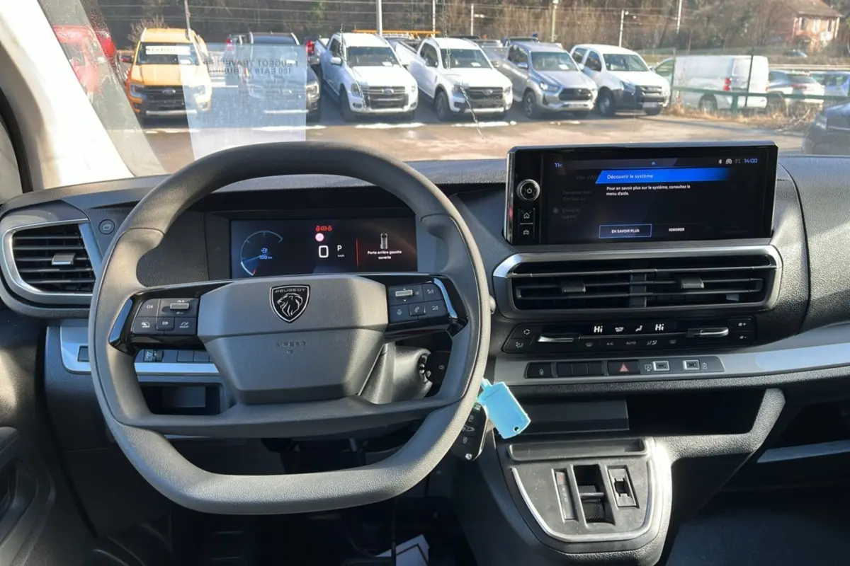 Vue intérieure centrée sur le volant multifonctions et l'écran tactile du tableau de bord du Peugeot Traveller gris titane.