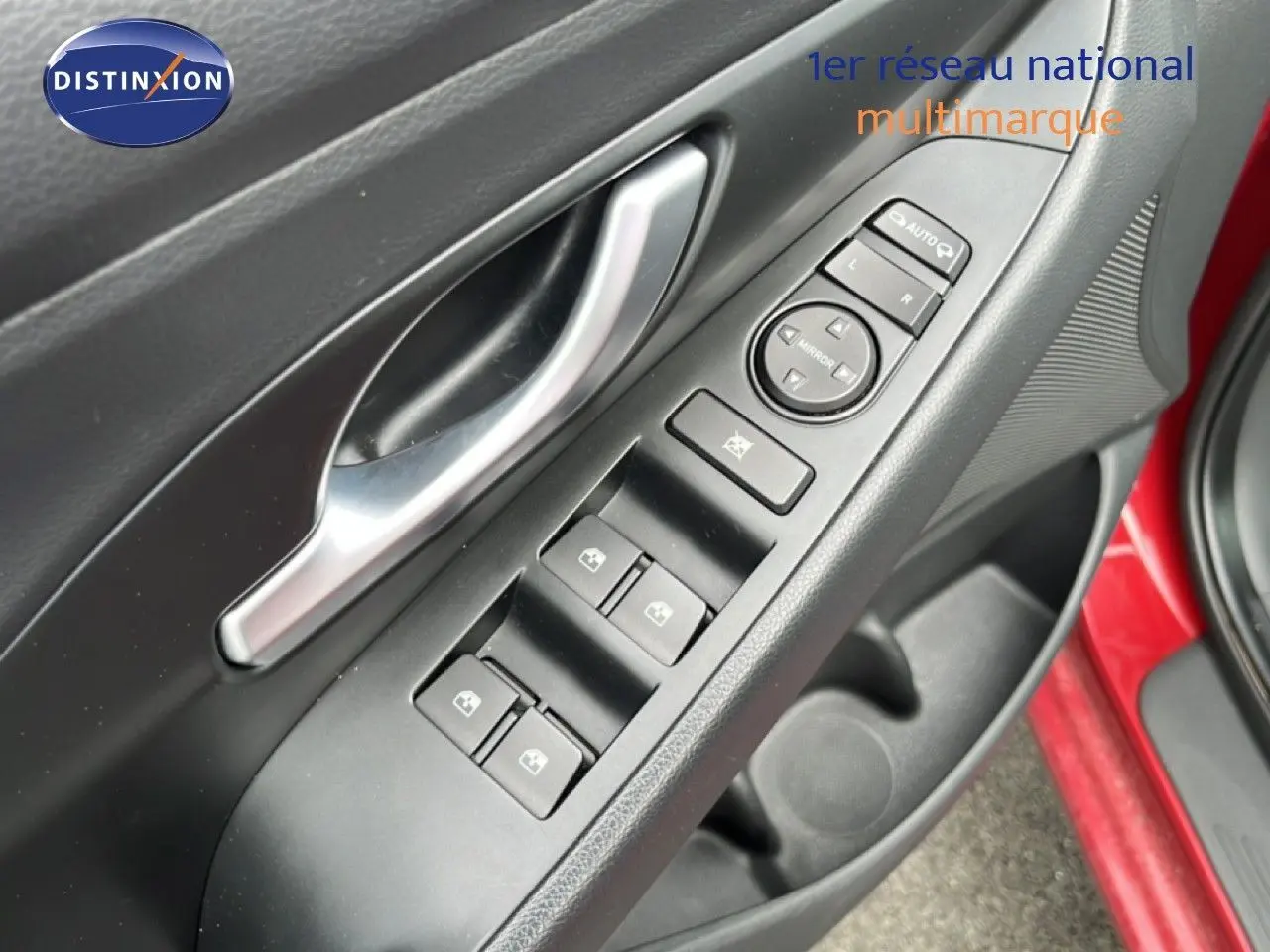 Gros plan sur la commande des vitres et rétroviseurs côté conducteur d'une Hyundai i30 SW rouge 2023.