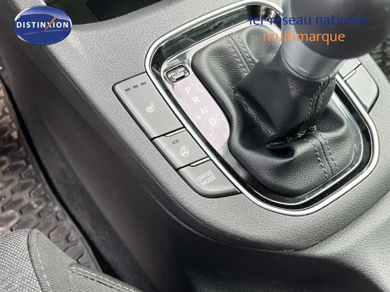 Gros plan sur la console centrale noire de la Hyundai i30 SW 2023, mettant en valeur le levier de vitesse automatique et les boutons chauffants.