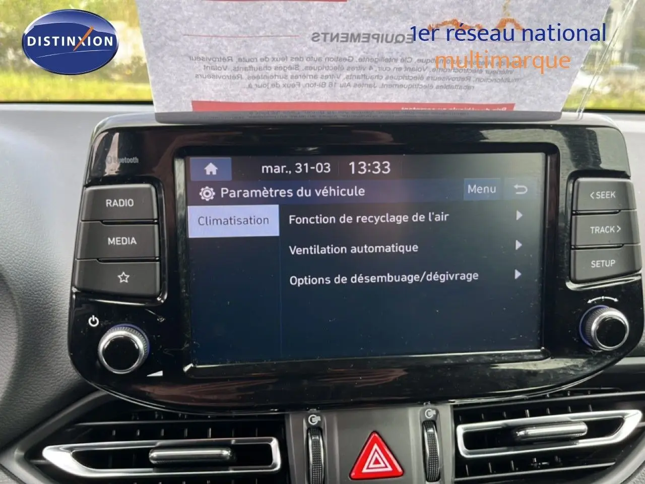 Écran tactile central du tableau de bord de la Hyundai i30 SW 2023 en Sunset Red, affichant les paramètres de climatisation.