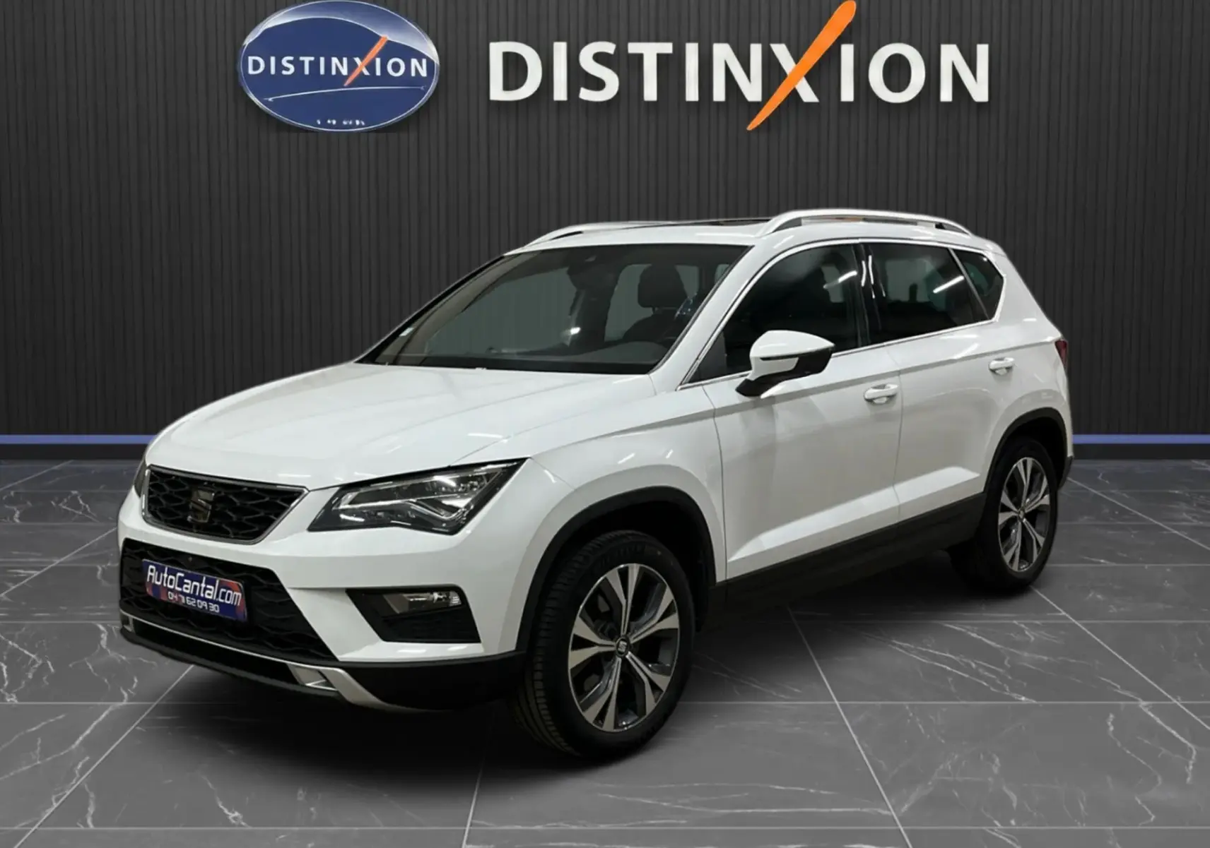 SEAT Ateca blanc en 3/4 avant droit, avec jantes alliage bicolores et toit ouvrant visible en intérieur showroom.
