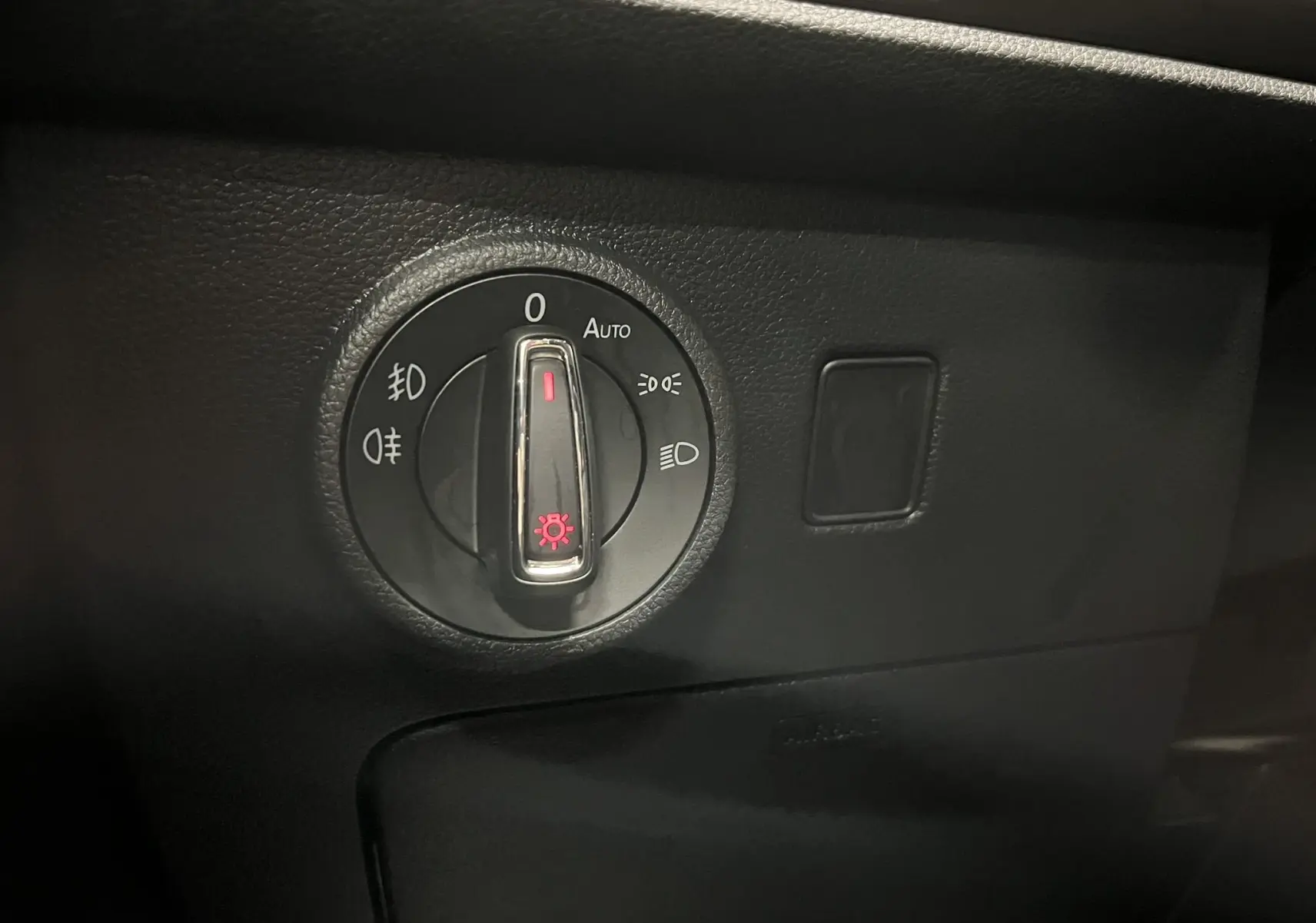 Gros plan sur la molette de réglage des phares du tableau de bord noir du SEAT Ateca blanc 2016.