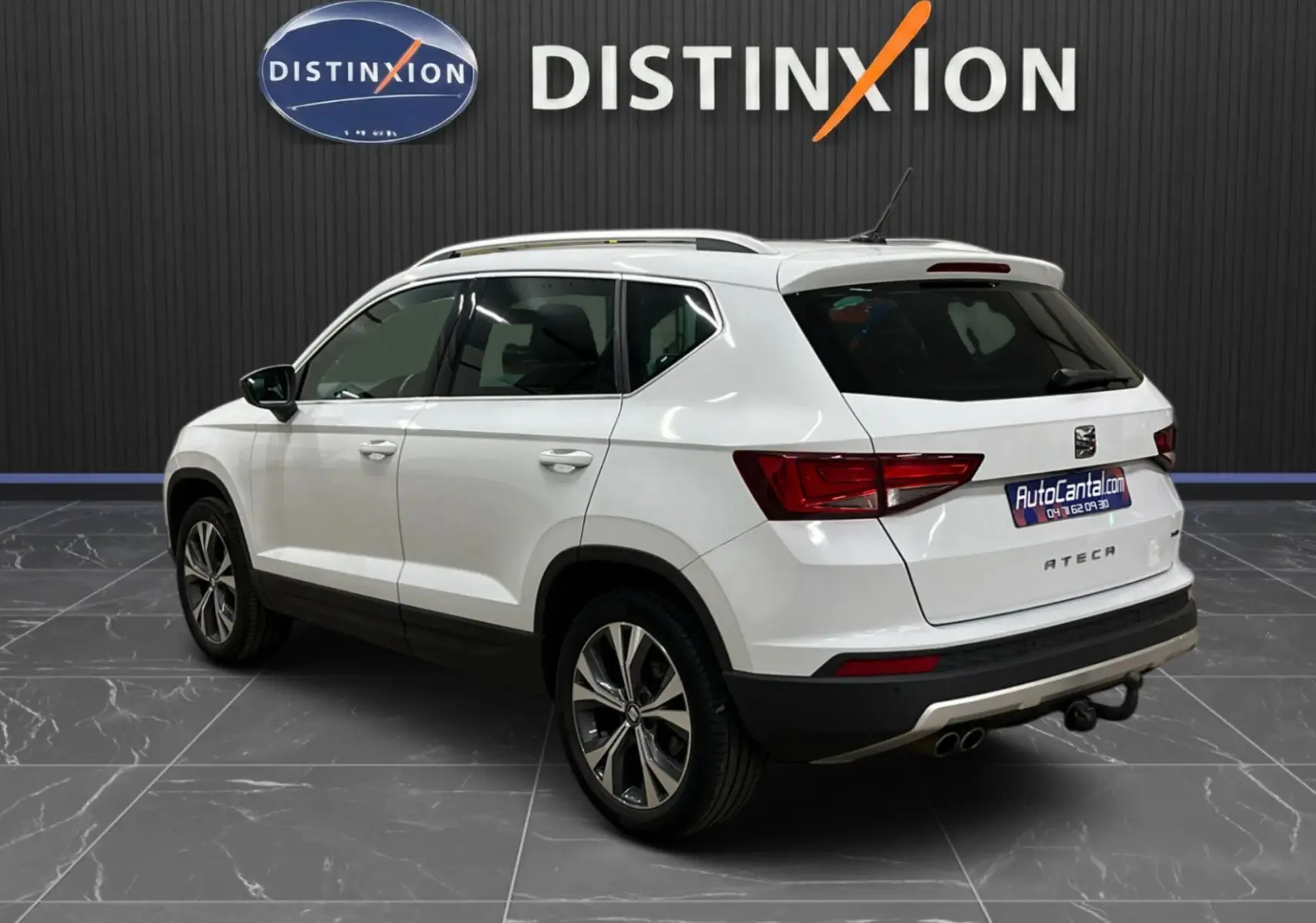 Vue 3/4 arrière droite d'un SEAT Ateca blanc 2016 avec barres de toit et attelage visible en intérieur showroom.