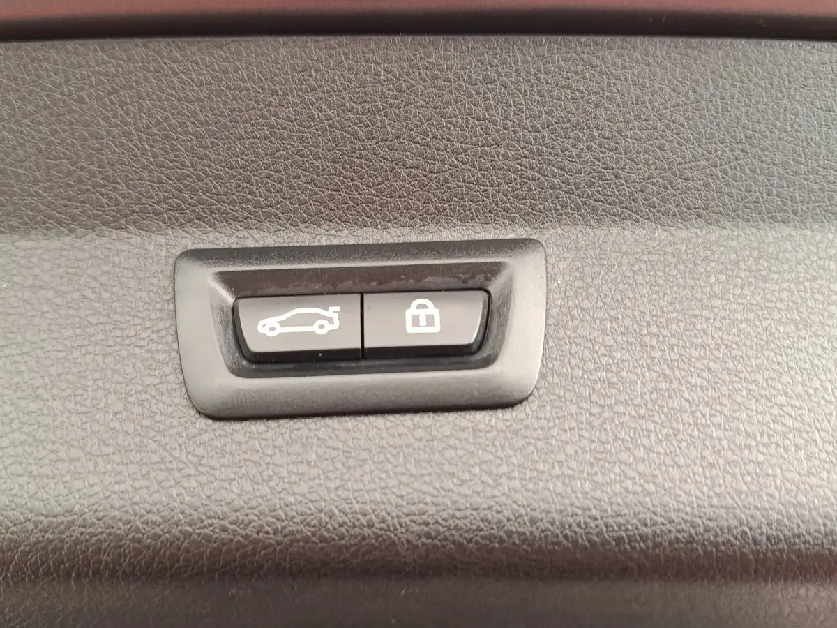 Gros plan sur les boutons d'ouverture et de verrouillage électrique du coffre d'une BMW Série 2 Gran Tourer gris clair.