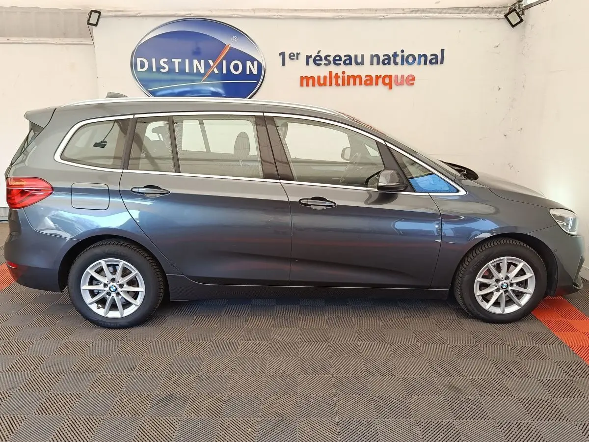 BMW Série 2 Gran Tourer 218i Lounge gris clair vue de profil côté gauche en intérieur showroom.