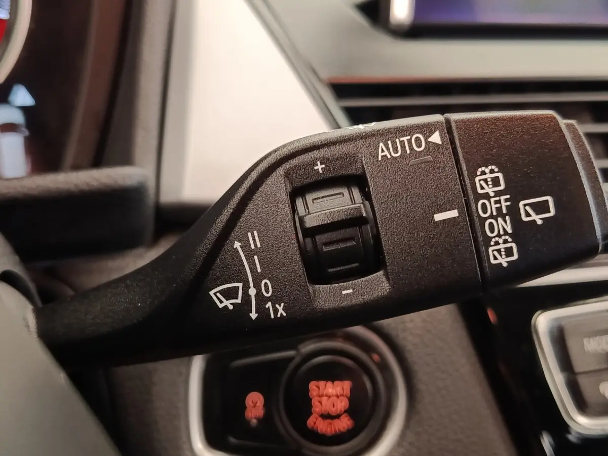 Gros plan sur la commande des essuie-glaces à gauche du volant dans l’habitacle d’une BMW Série 2 Gran Tourer gris clair.