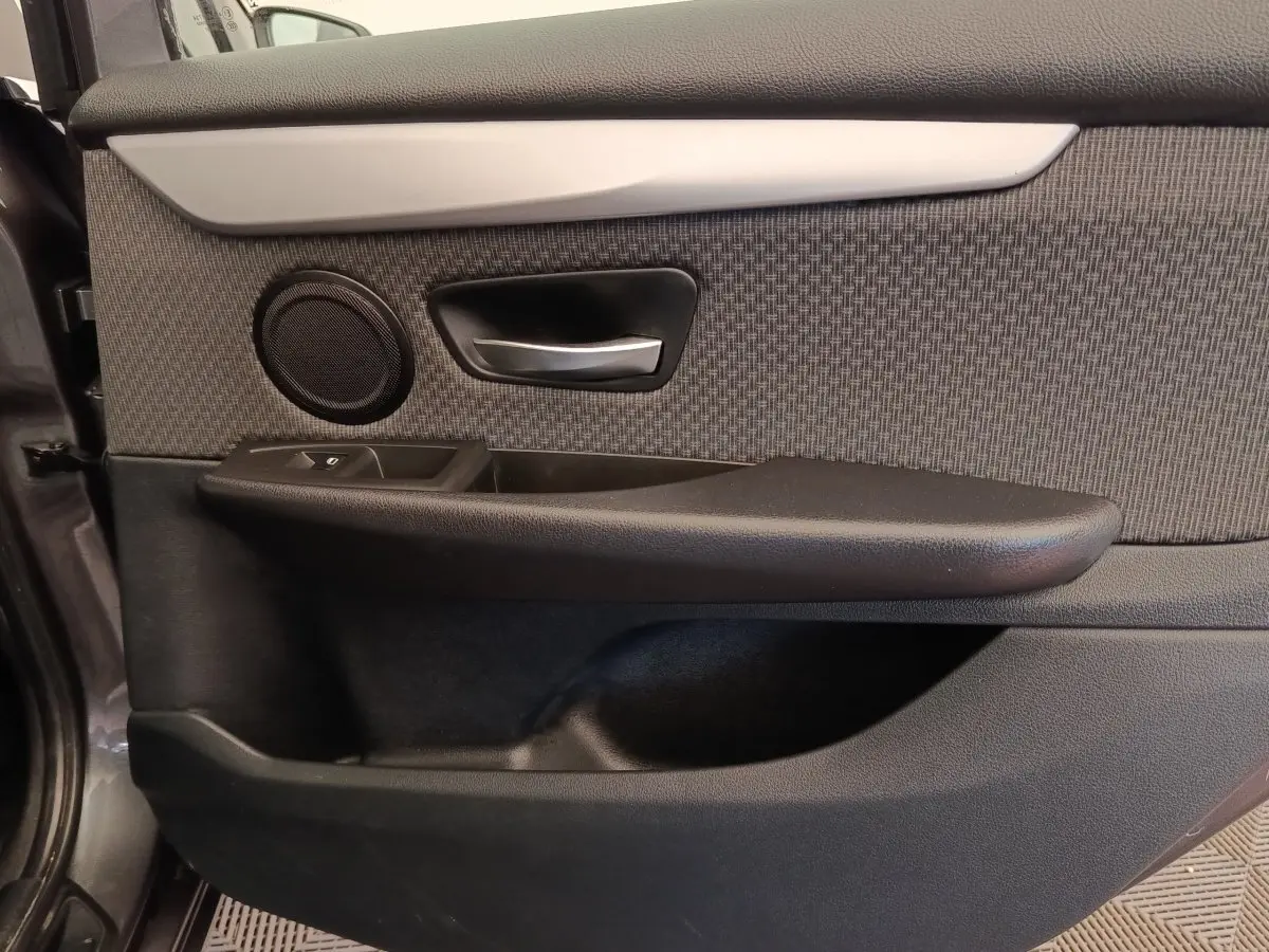 Gros plan sur la porte intérieure côté conducteur de la BMW Série 2 Gran Tourer gris clair, avec poignée alu et haut-parleur intégré.