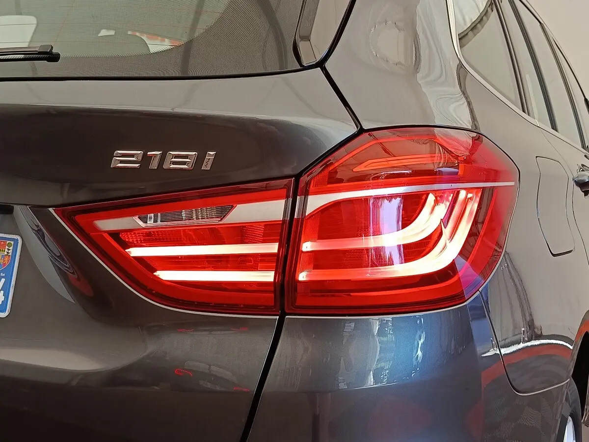 Gros plan sur le feu arrière droit allumé d'une BMW Série 2 Gran Tourer 218i gris clair, avec logo 218i visible.
