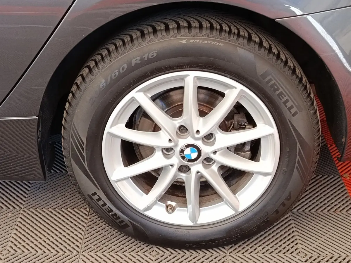 Gros plan sur la roue arrière droite d'une BMW Série 2 Gran Tourer 218i Lounge gris clair avec jante alliage 5 branches.