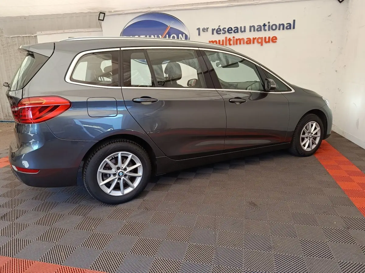 BMW Série 2 Gran Tourer gris clair vue de profil côté droit dans un showroom avec jantes alliage.
