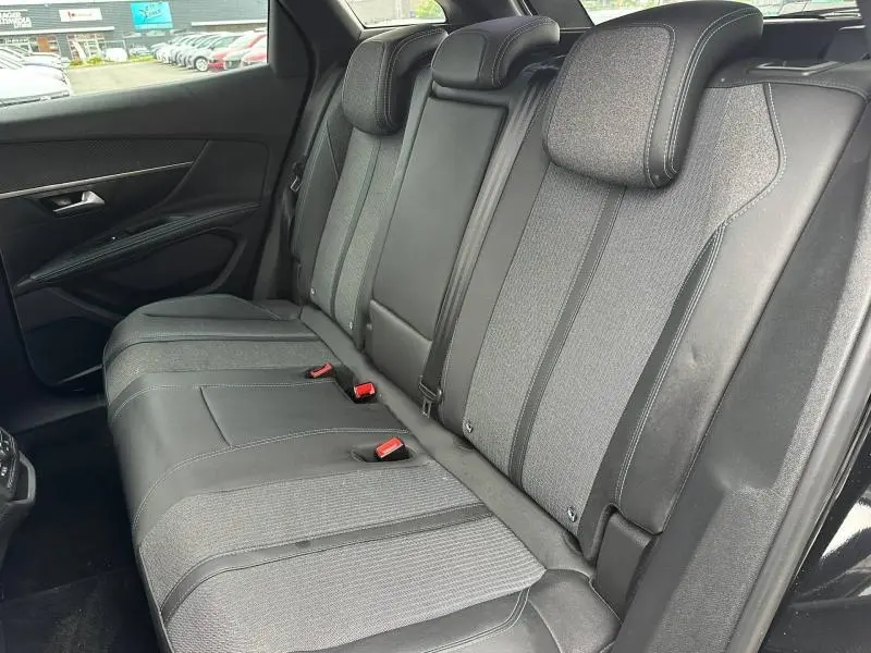 Vue latérale droite de la banquette arrière en tissu et cuir noir du Peugeot 3008 Hybride Rechargeable 2024, avec appuis-tête et ceintures visibles.
