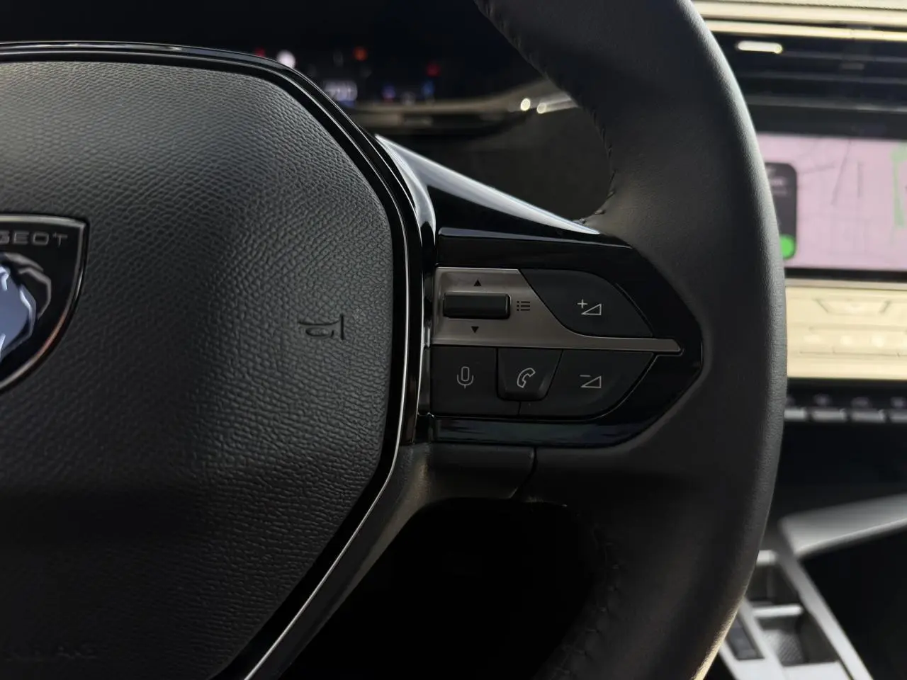Gros plan sur la partie droite du volant noir de la Peugeot 308 SW 2025 avec commandes intégrées et écran tactile en arrière-plan.