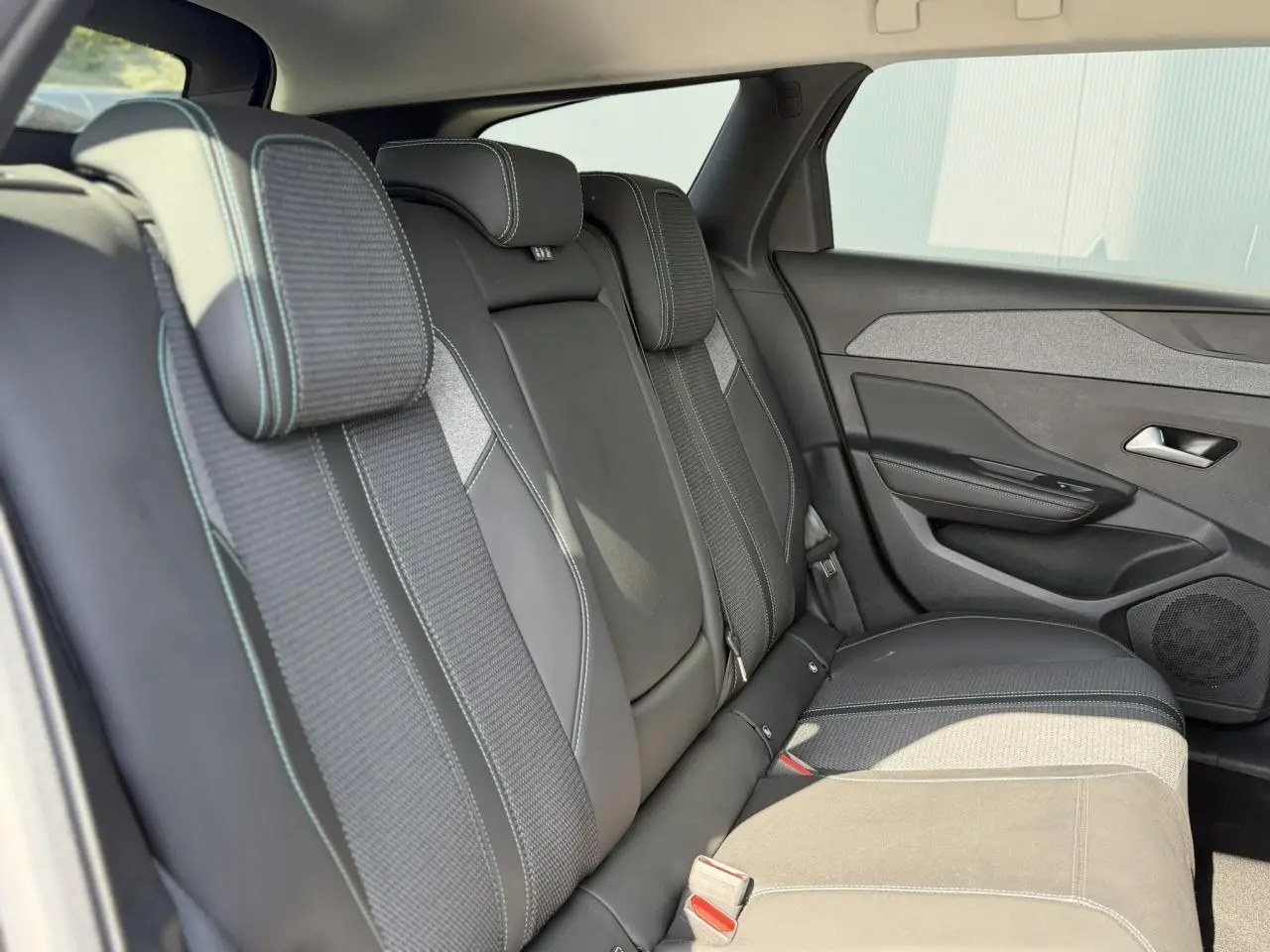 Vue latérale droite des sièges arrière en sellerie tri matières noire avec surpiqûres bleues du Peugeot 308 SW 2025.