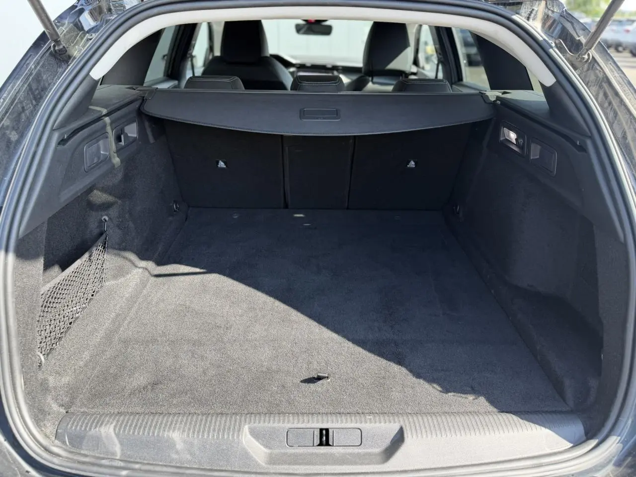 Coffre ouvert vu de l'arrière d'une Peugeot 308 SW noir Perla, espace de chargement spacieux et tapis noir.