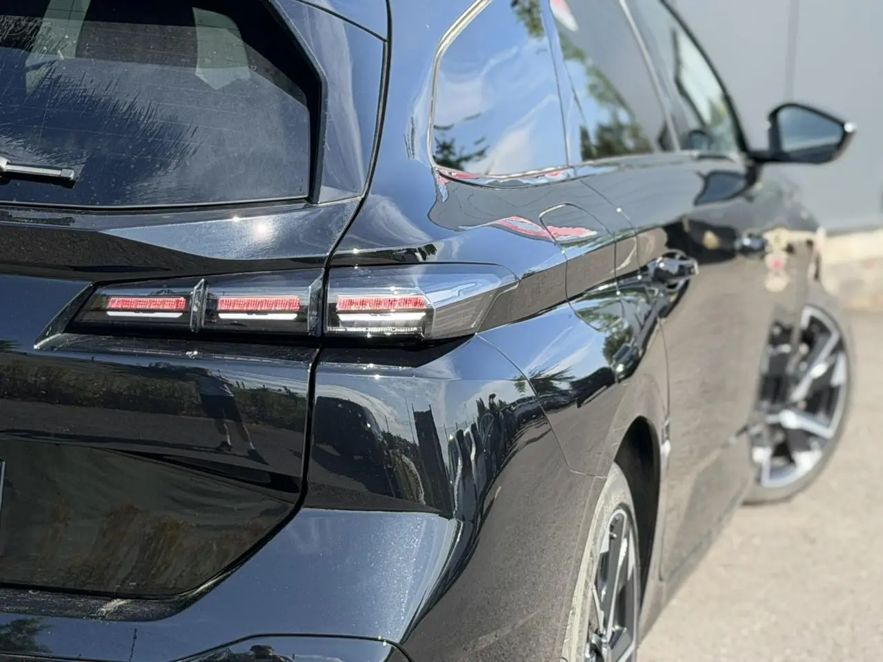 Vue 3/4 arrière droite de la Peugeot 308 SW noire Perla avec feux arrière LED et jantes alliage 17 pouces.