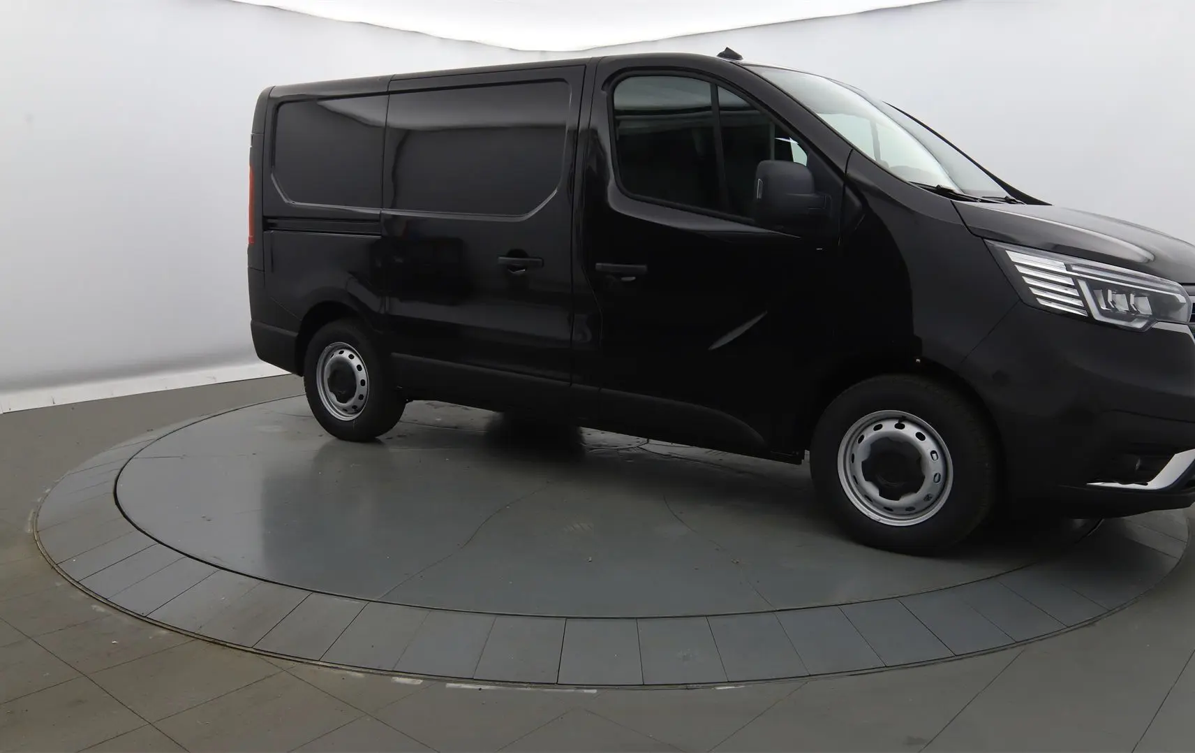 Renault Trafic Fourgon noir crépuscule en 3/4 avant droit, avec calandre chromée et phares LED visibles.