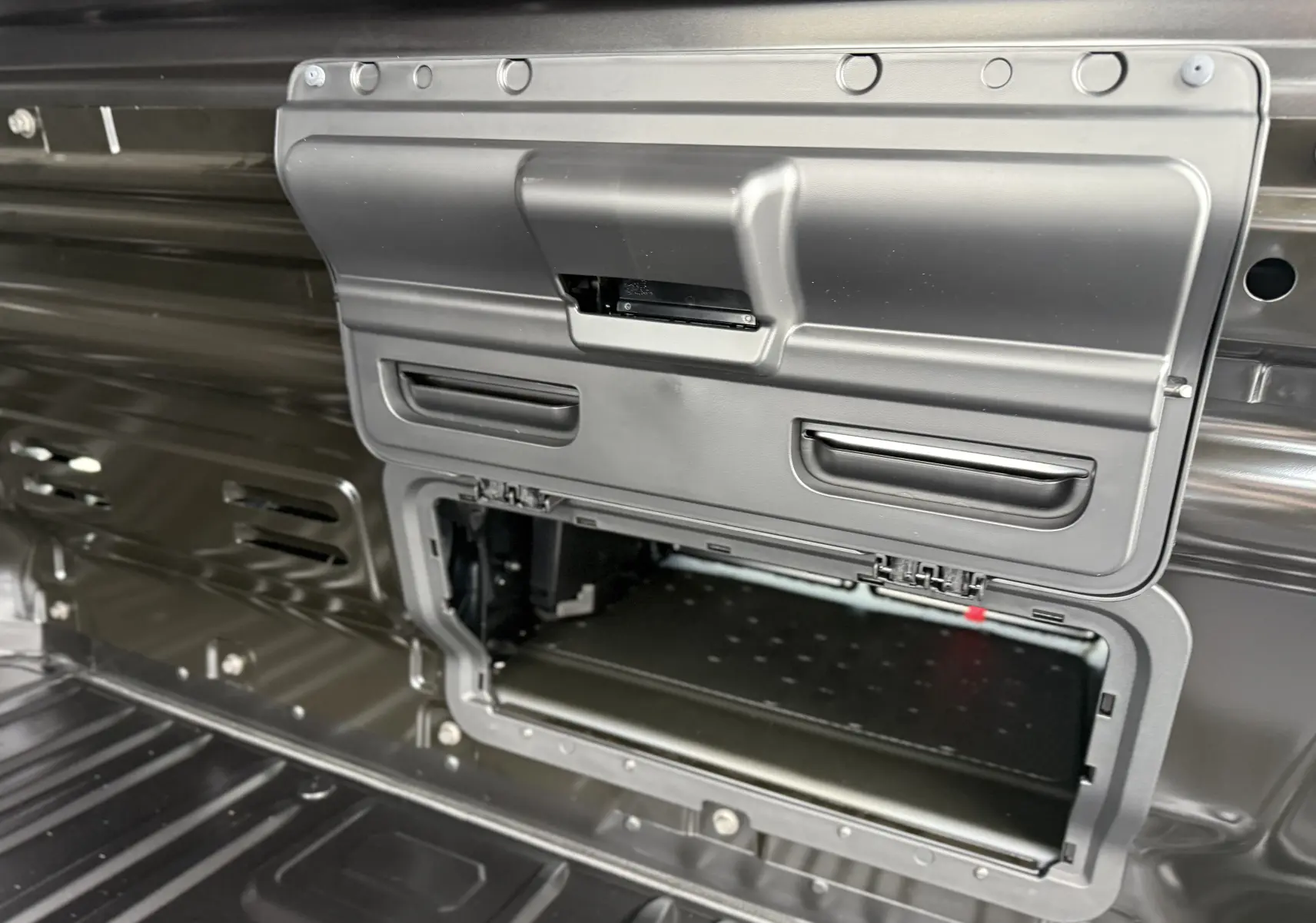 Détail intérieur du Renault Trafic Fourgon noir crépuscule montrant un compartiment de rangement ouvert dans la cloison arrière.