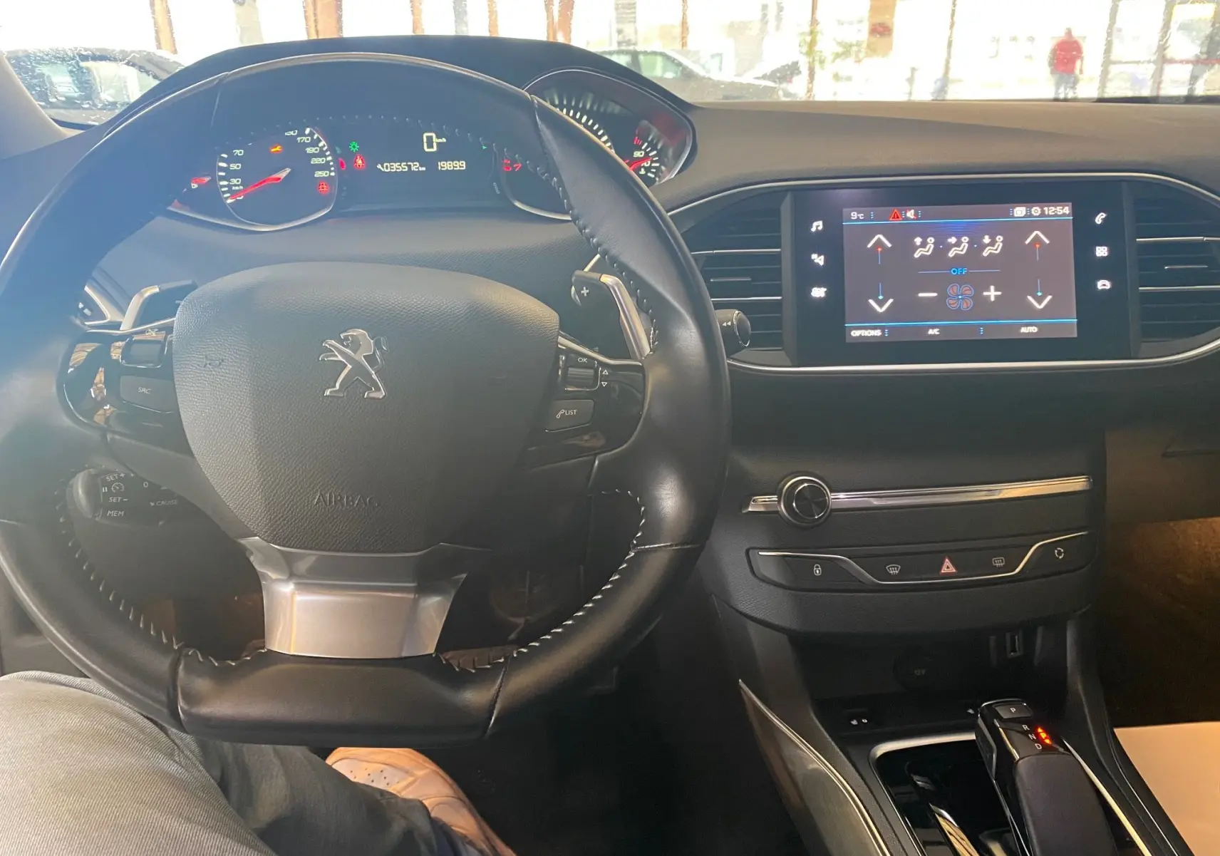 Vue intérieure centrée sur le volant et le tableau de bord noir d'une Peugeot 308 Allure blanche de 2020.