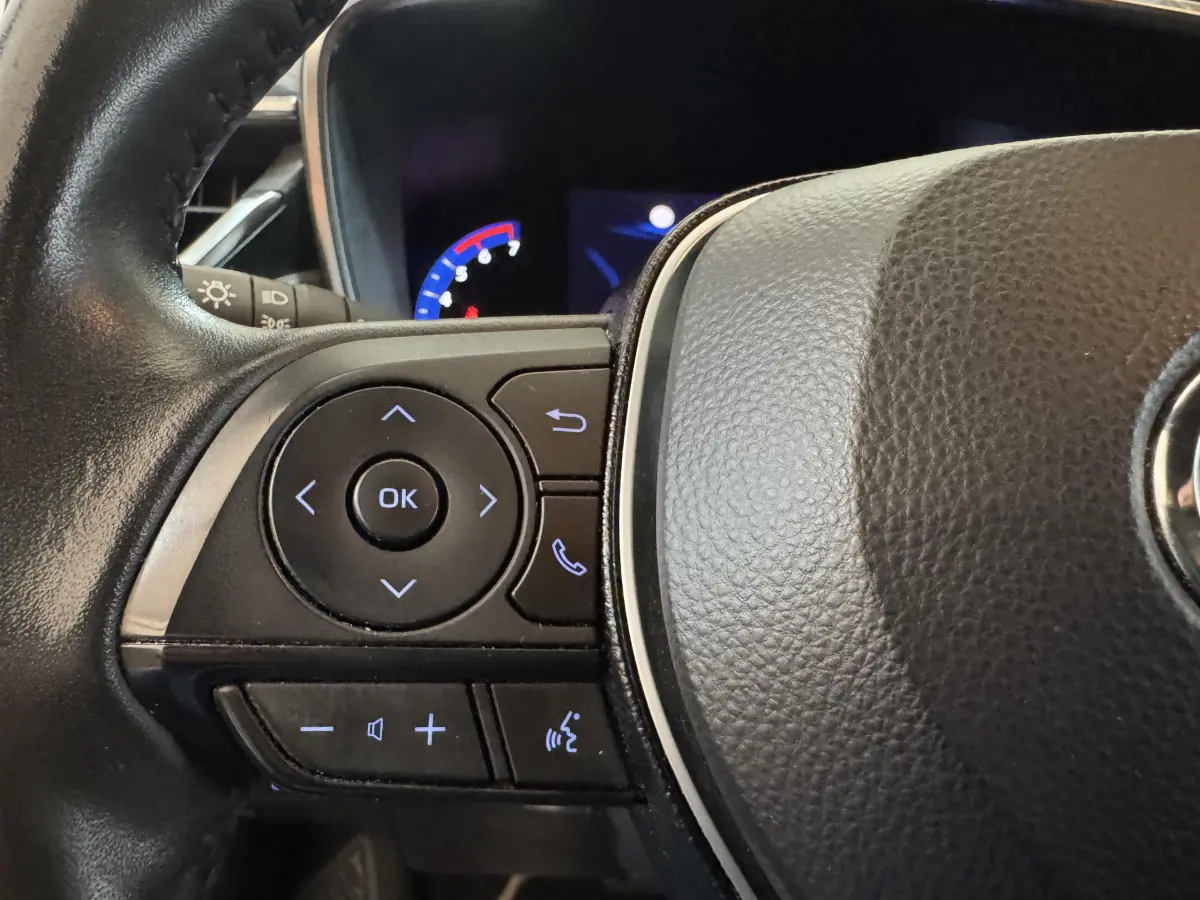 Gros plan sur les commandes multifonctions du volant cuir noir de la Toyota Corolla Hybride 122h Collection 2021.