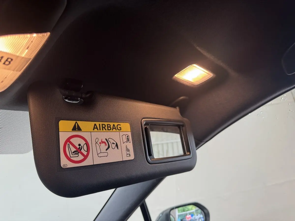 Pare-soleil côté conducteur avec miroir intégré et avertissement airbag dans l'habitacle noir de la Toyota Corolla hybride 2021.