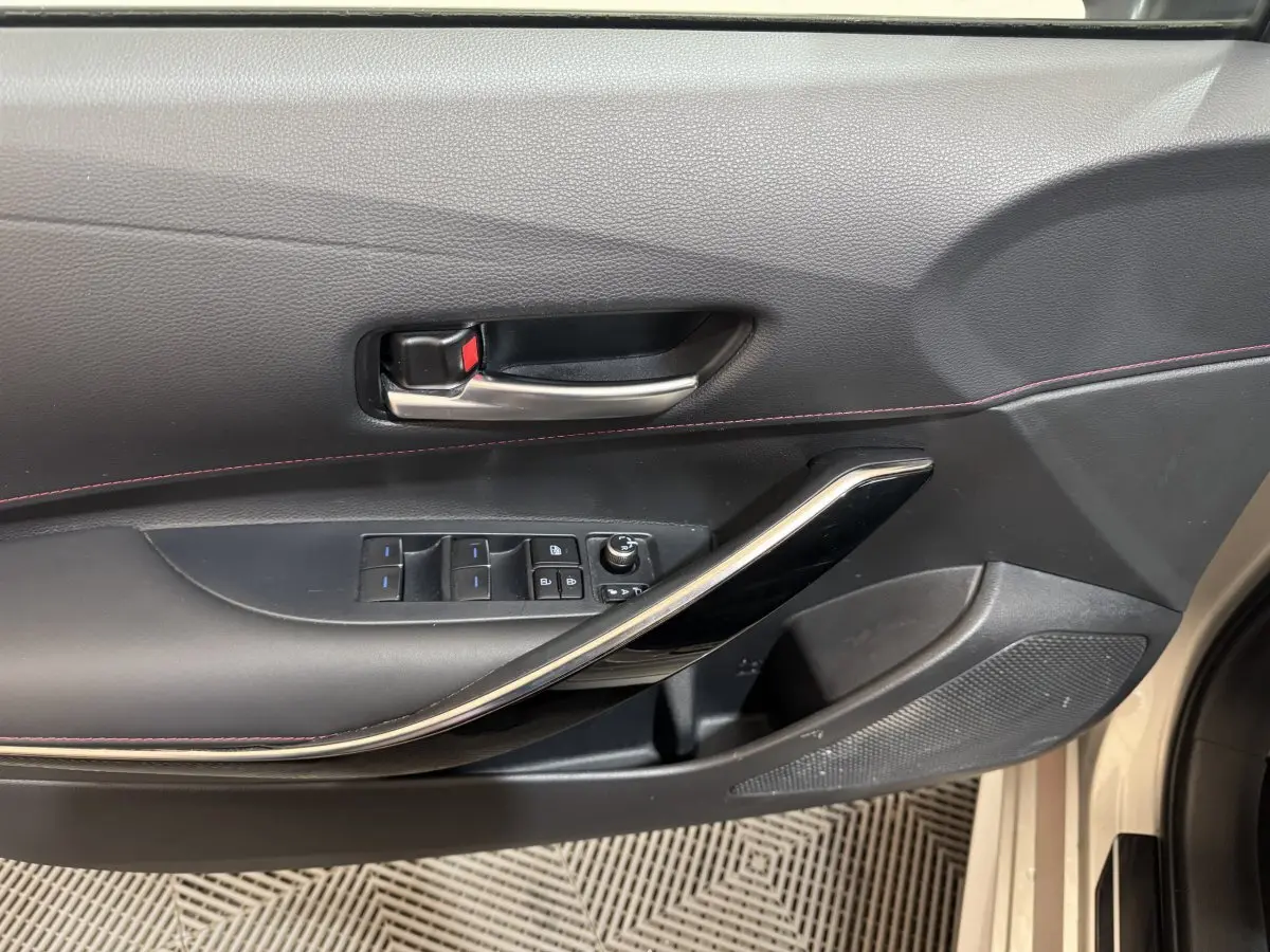 Gros plan sur la porte côté gauche de la Toyota Corolla Hybride 122h Collection 2021, avec commandes vitres et poignée noire.