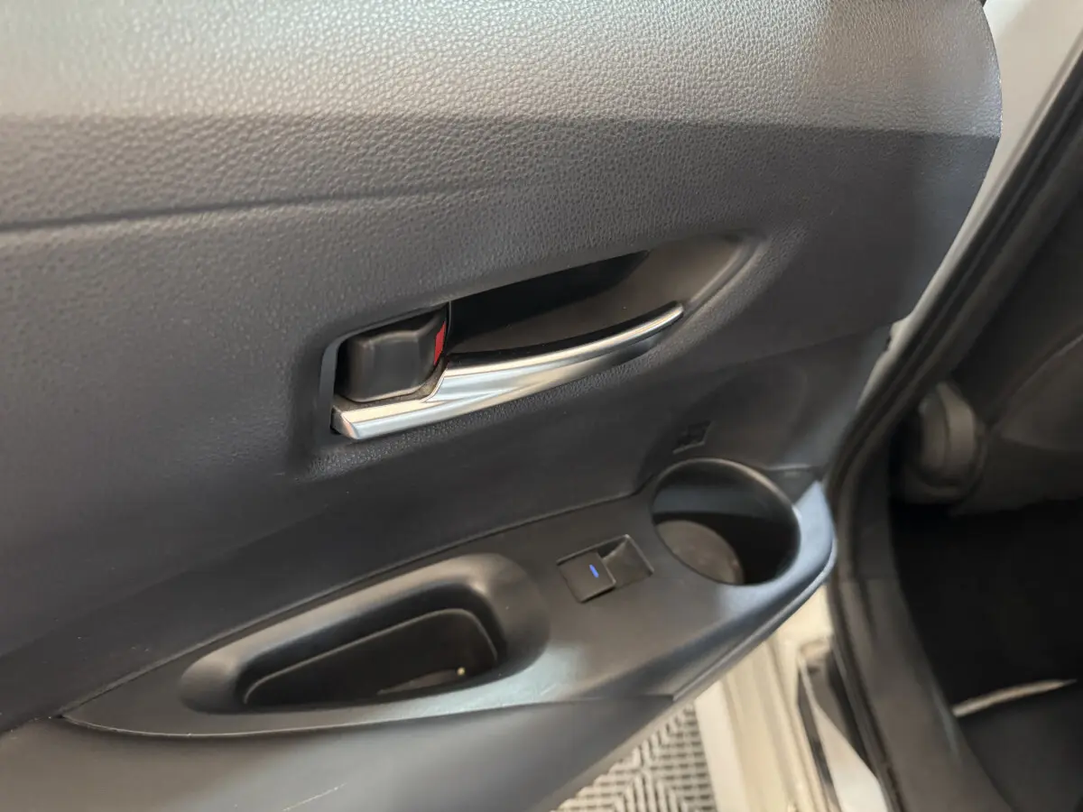 Poignée intérieure chromée et commande de fenêtre sur la portière arrière droite d'une Toyota Corolla gris clair hybride 2021.