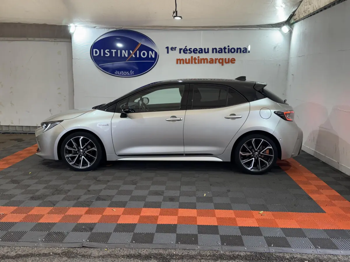 Profil côté gauche d'une Toyota Corolla Hybride 122h Collection gris clair avec toit noir et jantes alliage noires.