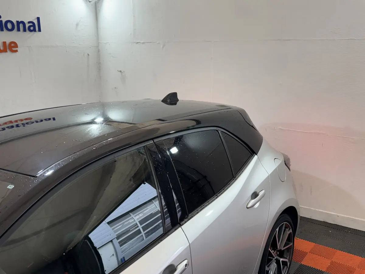 Vue arrière côté droit d'une Toyota Corolla Hybride 122h Collection gris clair avec toit noir brillant et vitres teintées.