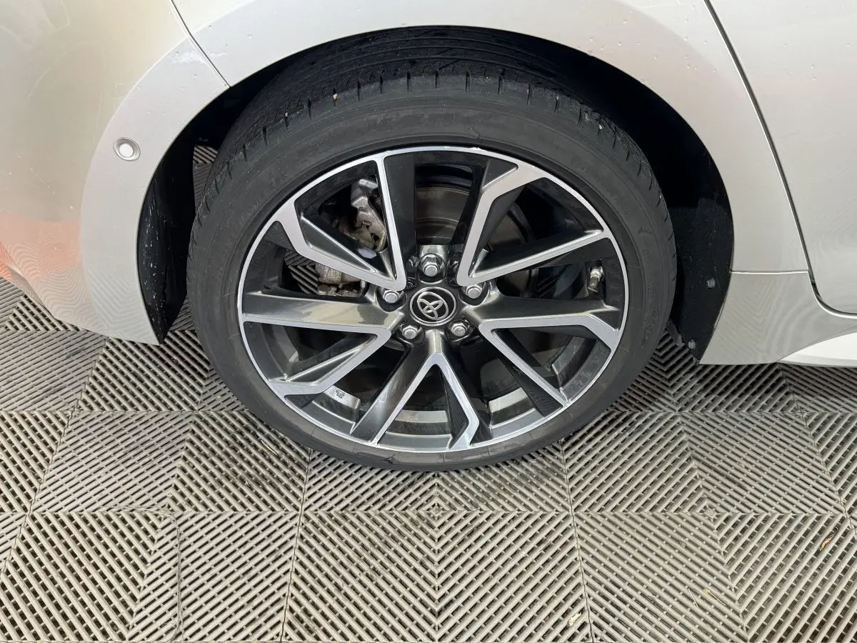 Gros plan sur la roue arrière droite gris clair de la Toyota Corolla Hybride 122h avec jante alliage noire et argentée.