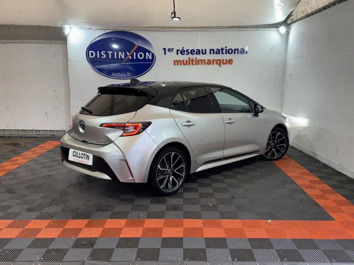 Toyota Corolla Hybride 122h gris clair vue 3/4 arrière droit avec toit noir et jantes alliage distinctives