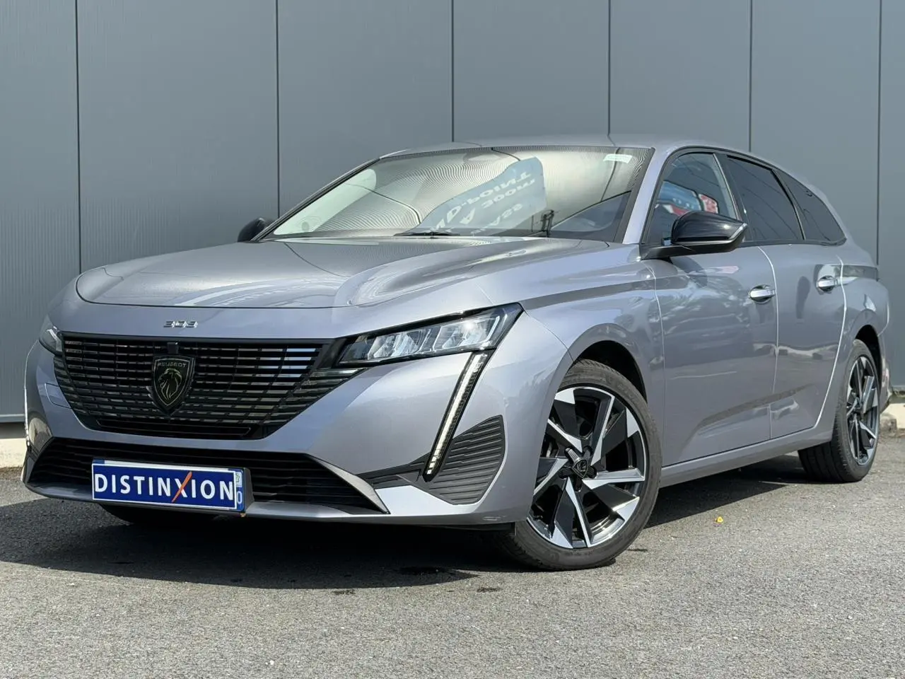 Peugeot 308 SW gris Artense en 3/4 avant droit, avec calandre noire et jantes alliage 17 pouces.