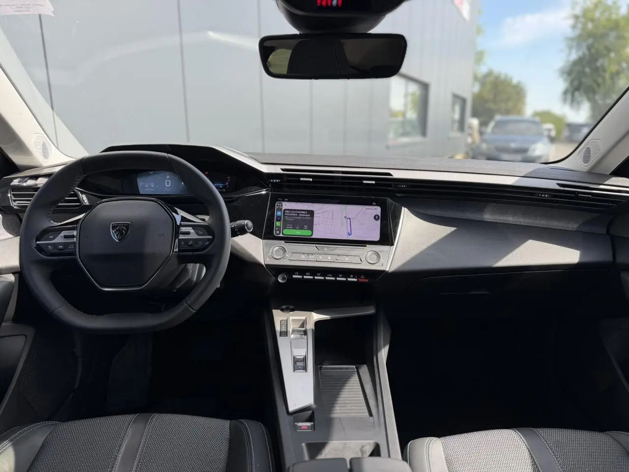 Vue intérieure avant du Peugeot 308 SW 2025 avec tableau de bord moderne et écran tactile central lumineux.