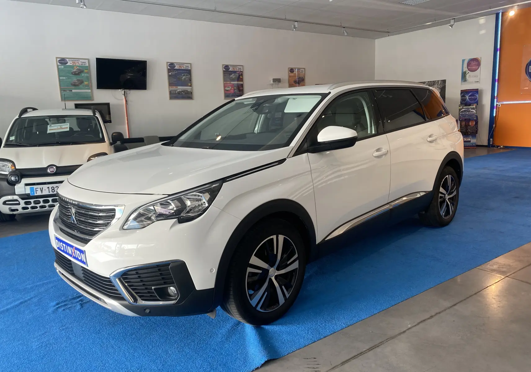Peugeot 5008 blanc blanquise en 3/4 avant droit, avec jantes alliage et attelage neuf visible en intérieur showroom.