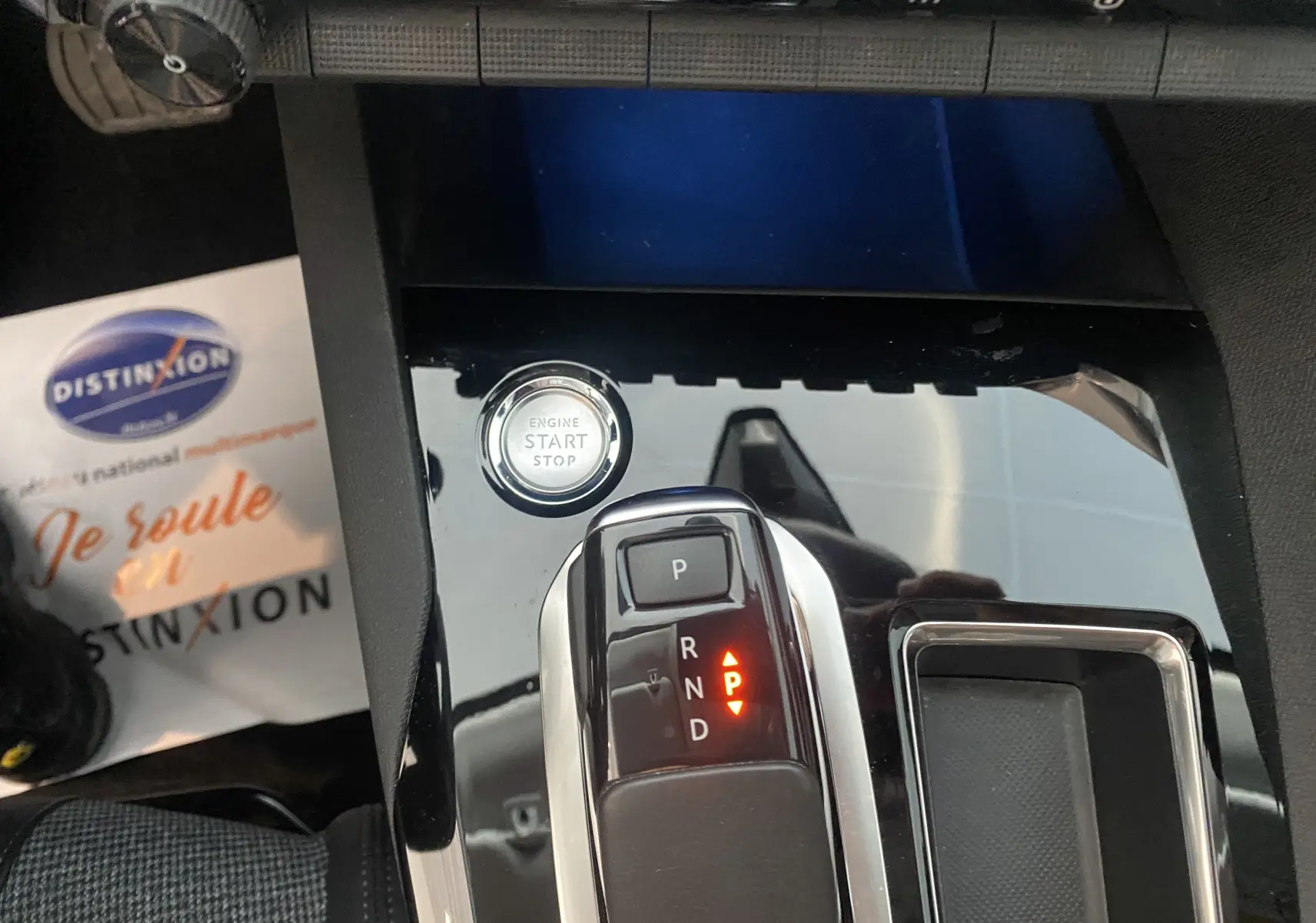 Le levier de vitesses automatique et bouton start/stop sur la console noire brillante d'un Peugeot 5008 blanc.