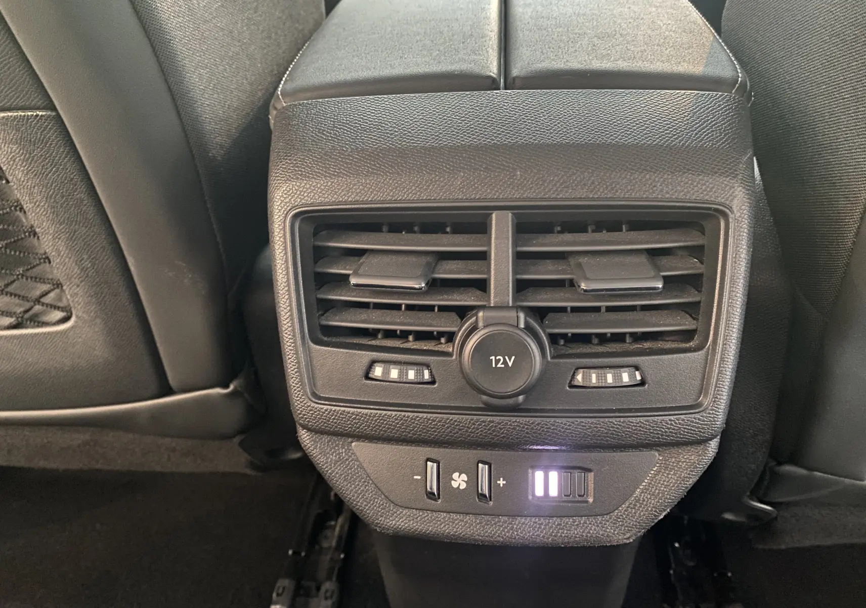 Vue rapprochée des commandes de ventilation arrière et prise 12V dans l'habitacle noir du Peugeot 5008 blanc.